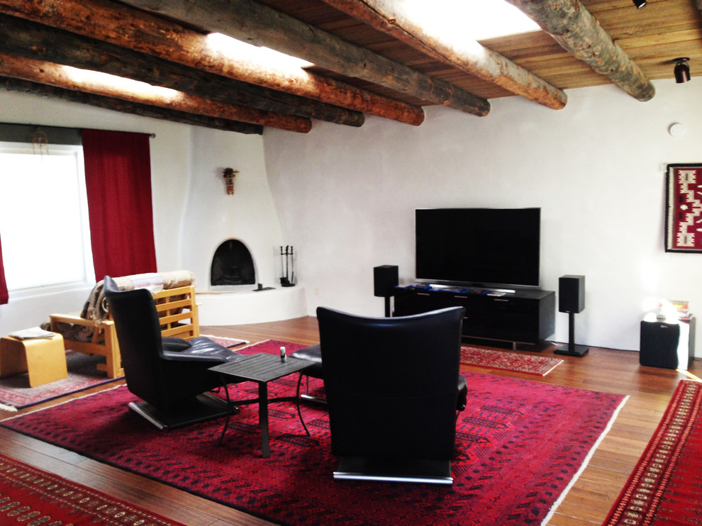 Источник вдохновения для домашнего уюта: изолированная гостиная комната среднего размера в стиле фьюжн с белыми стенами, полом из бамбука, угловым камином, фасадом камина из штукатурки и телевизором на стене