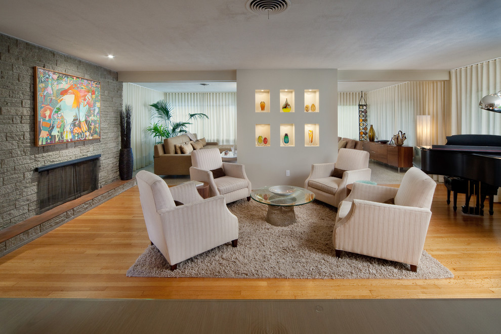 Cette image montre un salon minimaliste avec une salle de musique, un sol en bois brun, une cheminée standard et un manteau de cheminée en pierre.