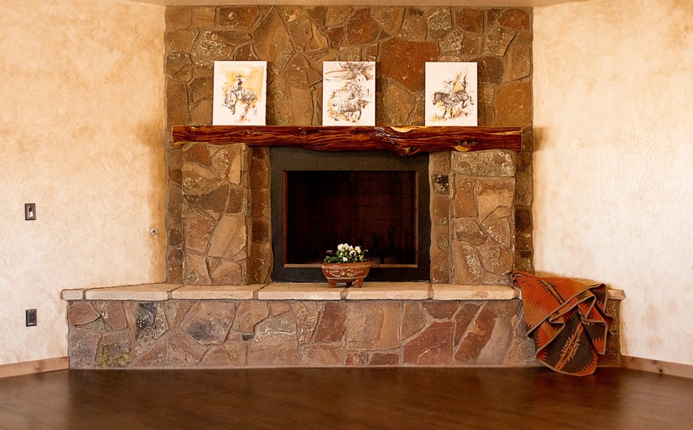 Mittelgroßes, Fernseherloses, Offenes Uriges Wohnzimmer mit beiger Wandfarbe, dunklem Holzboden, Eckkamin und Kaminumrandung aus Stein in Phoenix