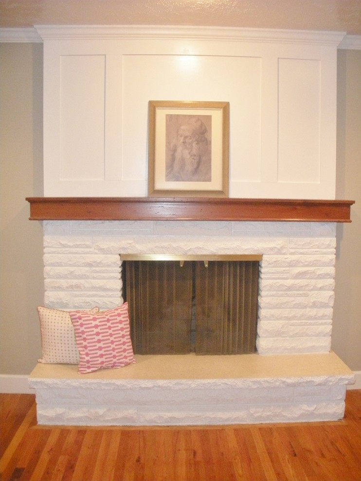 Réalisation d'un petit salon tradition avec un mur beige, un sol en bois brun et un manteau de cheminée en pierre.
