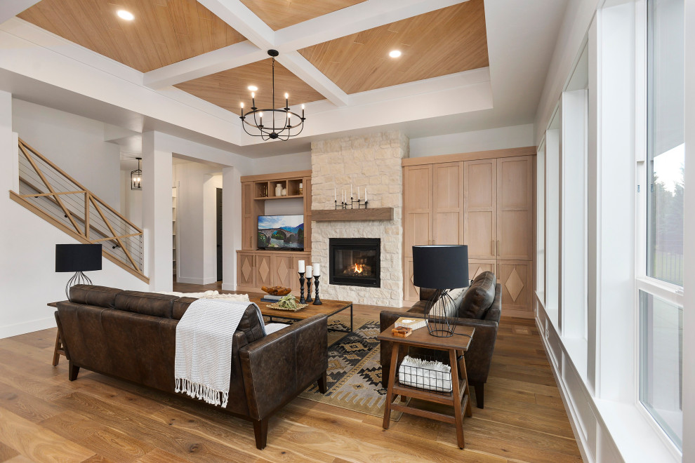 Large farmhouse open plan living room in Boise with white walls, medium hardwood flooring, a standard fireplace, a stone fireplace surround, a built-in media unit and a coffered ceiling.