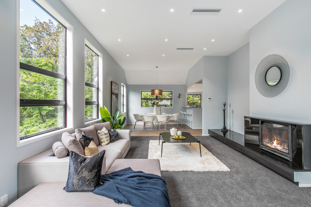 Идея дизайна: большая гостиная комната в современном стиле с синими стенами, ковровым покрытием, стандартным камином, фасадом камина из плитки и серым полом без телевизора