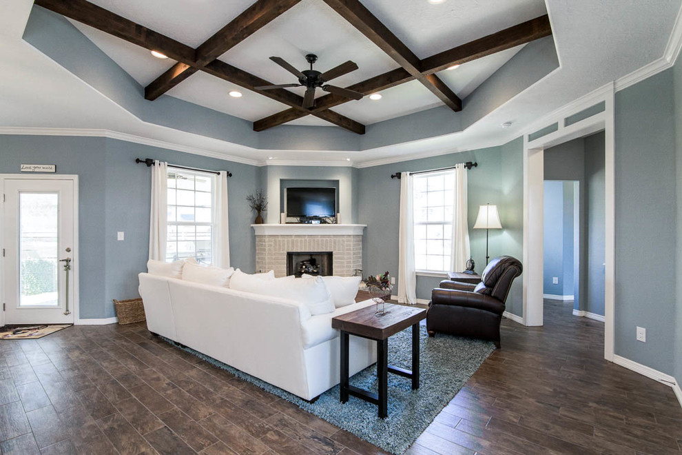 Источник вдохновения для домашнего уюта: открытая гостиная комната в стиле кантри с синими стенами, угловым камином, фасадом камина из кирпича и коричневым полом