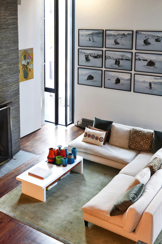 На фото: гостиная комната в стиле модернизм с фасадом камина из камня с