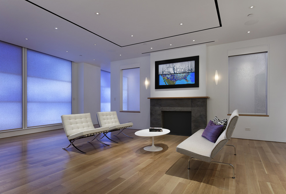 Свежая идея для дизайна: большая открытая гостиная комната в современном стиле с скрытым телевизором, светлым паркетным полом, белыми стенами, стандартным камином и фасадом камина из камня - отличное фото интерьера