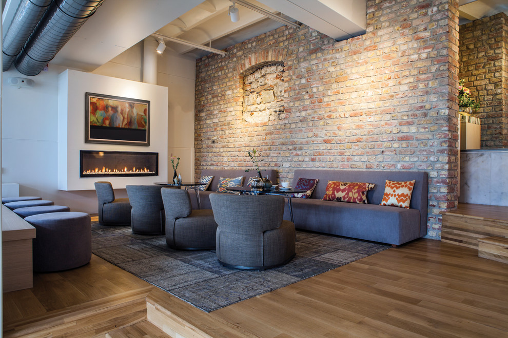 Imagen de salón abierto actual grande con suelo de madera en tonos medios, chimenea lineal y televisor retractable