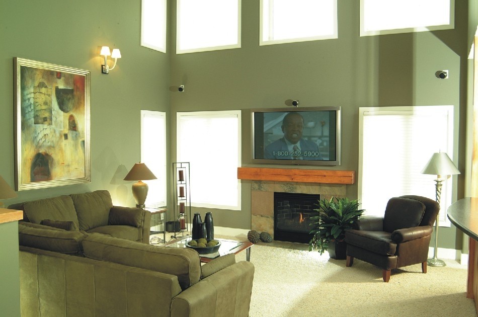 Klassisk inredning av ett mellanstort vardagsrum, med heltäckningsmatta, en standard öppen spis, en spiselkrans i trä, en väggmonterad TV och brunt golv