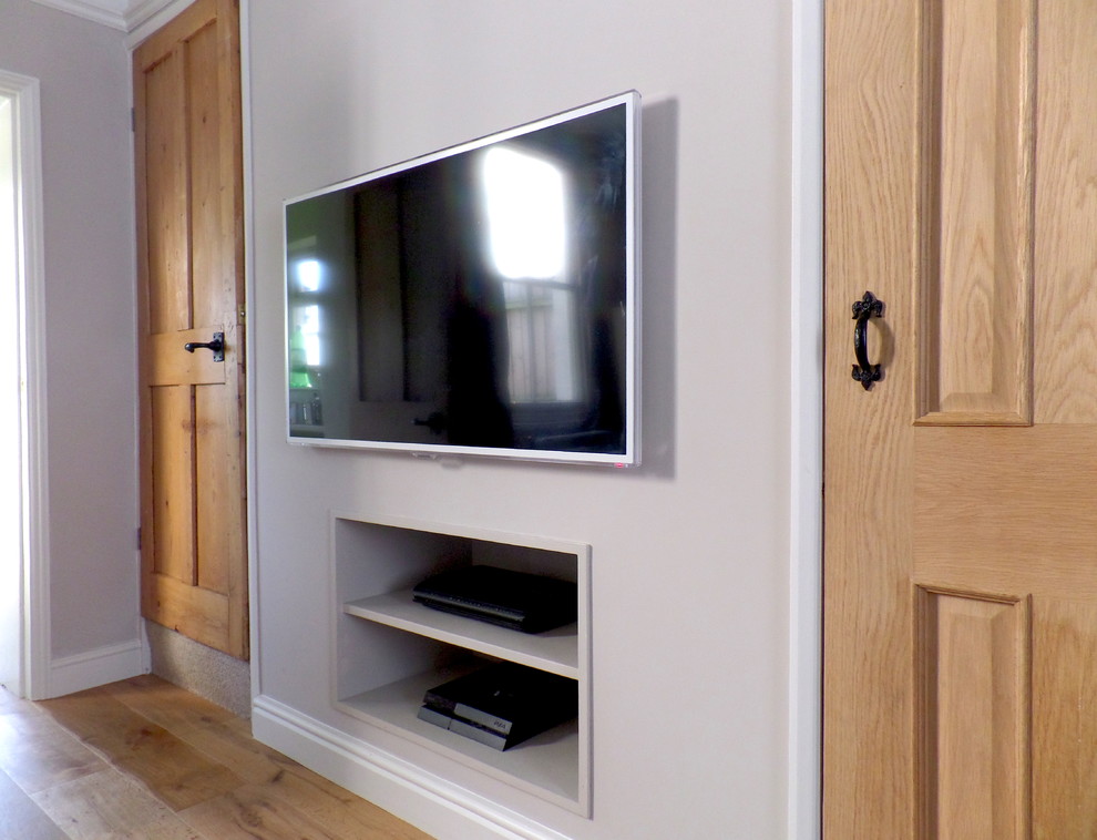 Идея дизайна: гостиная комната в современном стиле с серыми стенами, паркетным полом среднего тона и телевизором на стене