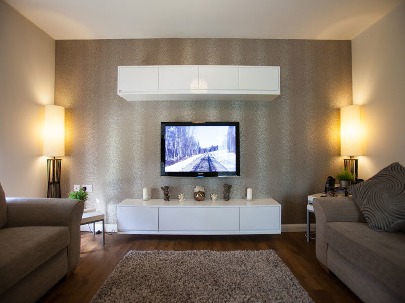 Inspiration för mellanstora moderna allrum med öppen planlösning, med beige väggar, mellanmörkt trägolv och en väggmonterad TV