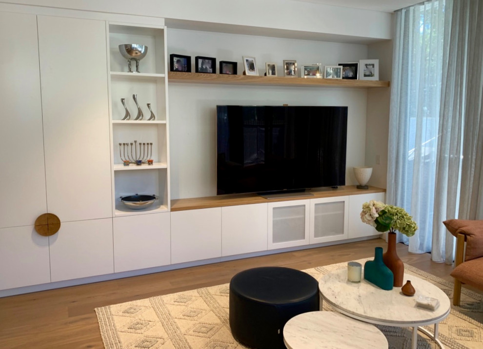 Diseño de salón actual de tamaño medio con paredes blancas, suelo de madera clara y televisor colgado en la pared