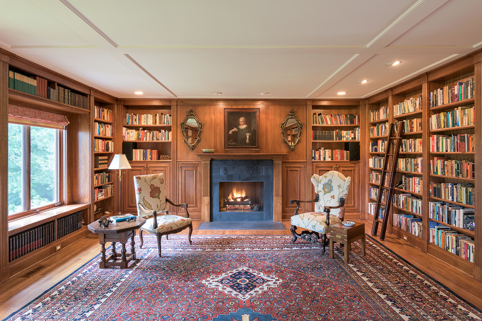 Exemple d'un grand salon chic ouvert avec une bibliothèque ou un coin lecture, un sol en bois brun, une cheminée standard, aucun téléviseur et un manteau de cheminée en pierre.