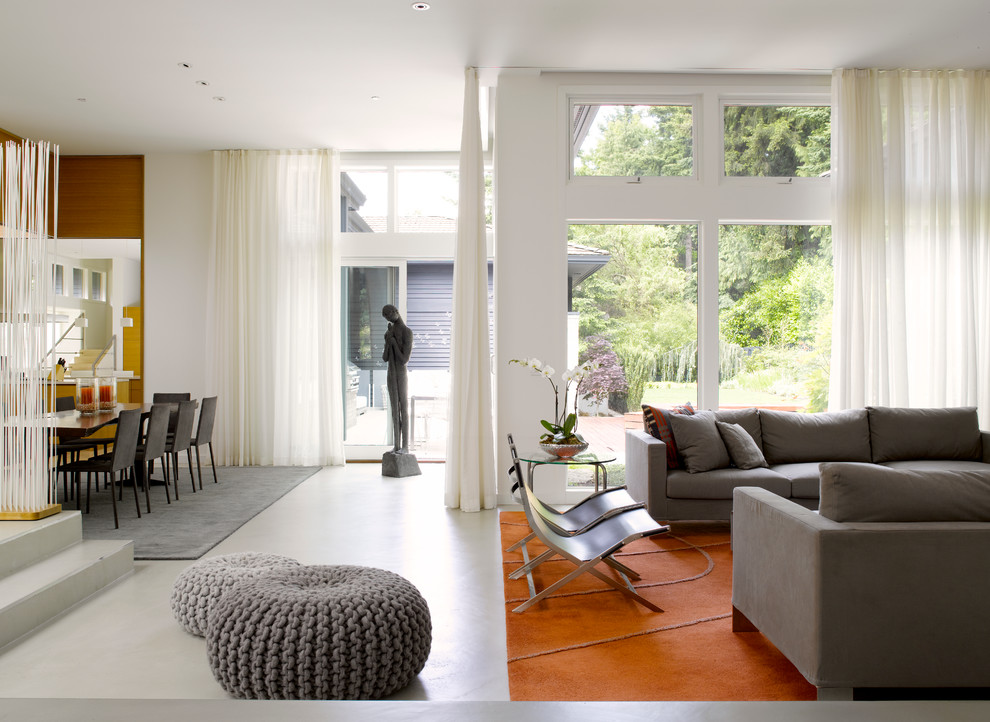 На фото: открытая гостиная комната в современном стиле с белыми стенами и бетонным полом