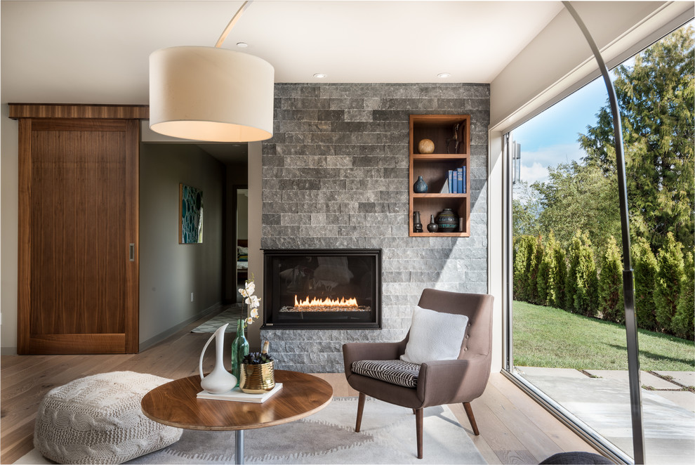 Esempio di un soggiorno design con pareti grigie, camino classico, pavimento marrone e parquet chiaro