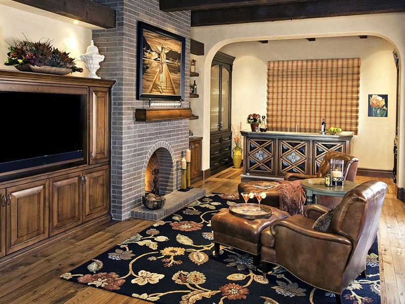 Réalisation d'un salon tradition de taille moyenne et fermé avec un bar de salon, un mur blanc, un sol en bois brun, une cheminée standard, un manteau de cheminée en brique, un téléviseur encastré et un sol marron.