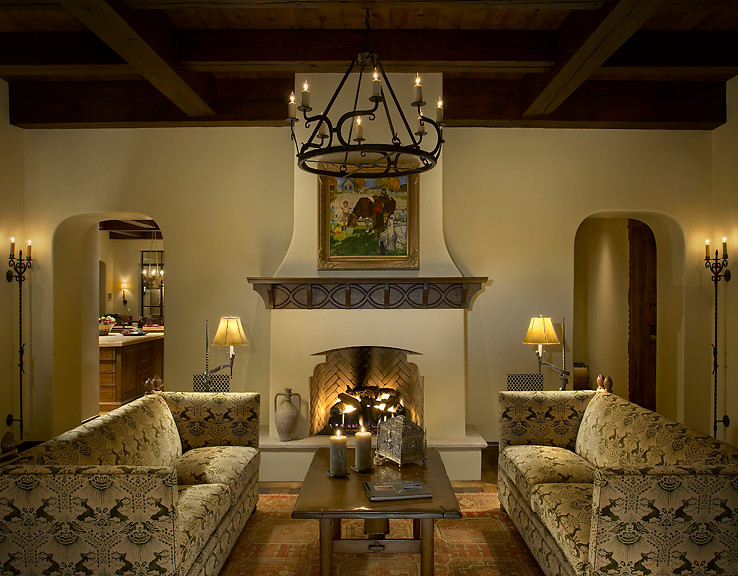 Exemple d'un grand salon méditerranéen fermé avec un mur beige, un sol en bois brun, une cheminée standard, un manteau de cheminée en plâtre et aucun téléviseur.