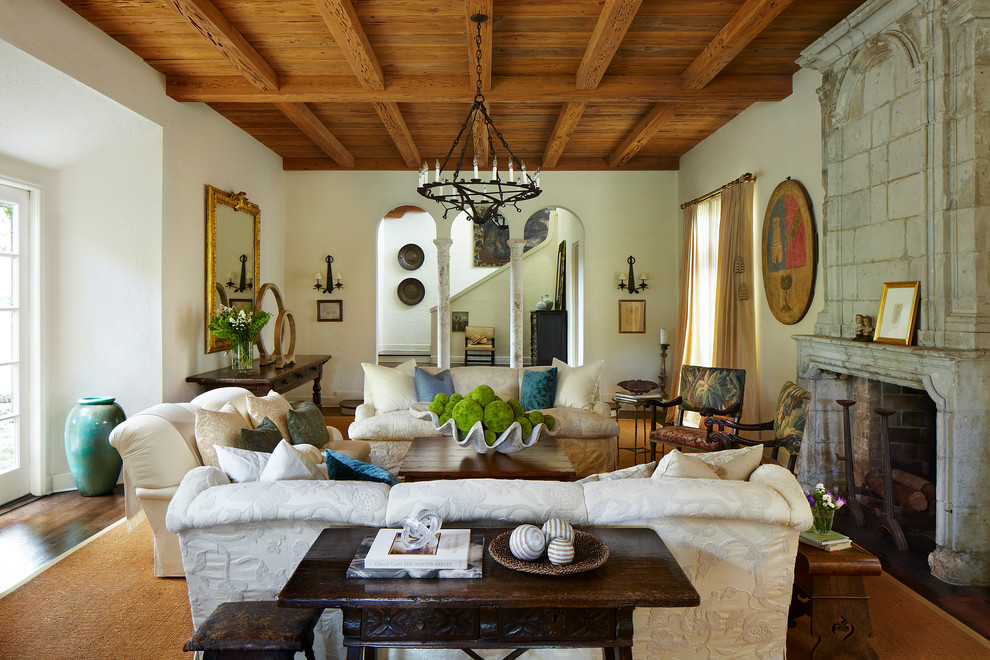 Imagen de salón para visitas mediterráneo con paredes blancas, suelo de madera en tonos medios, todas las chimeneas y marco de chimenea de piedra