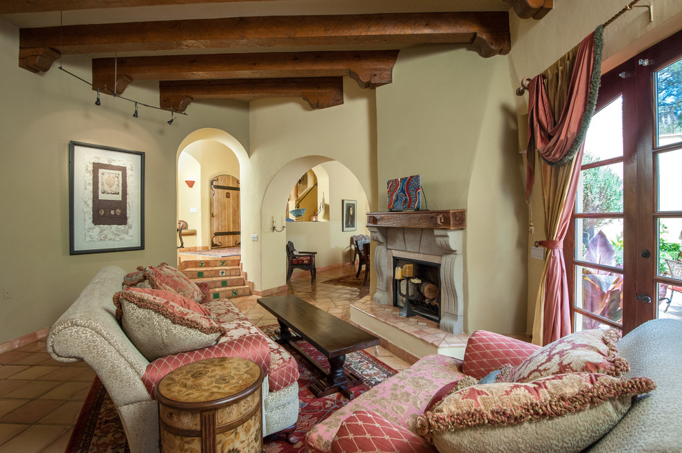 Esempio di un soggiorno mediterraneo con pareti beige, pavimento in terracotta, camino classico e nessuna TV