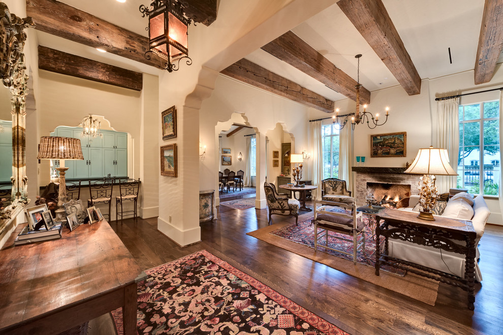 Photo of a large mediterranean formal open plan living room in Houston with white walls, dark hardwood flooring, a standard fireplace, a brick fireplace surround and no tv.