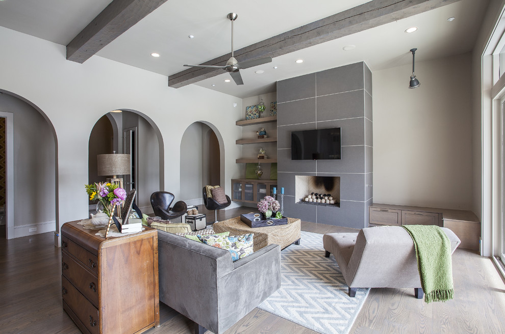 Repräsentatives Mediterranes Wohnzimmer mit grauer Wandfarbe, hellem Holzboden, Kamin, gefliester Kaminumrandung und TV-Wand in Dallas