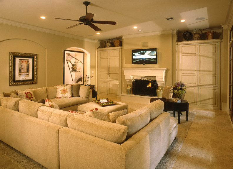 Immagine di un grande soggiorno chic aperto con pareti beige, pavimento in travertino, camino classico, cornice del camino in legno e TV a parete