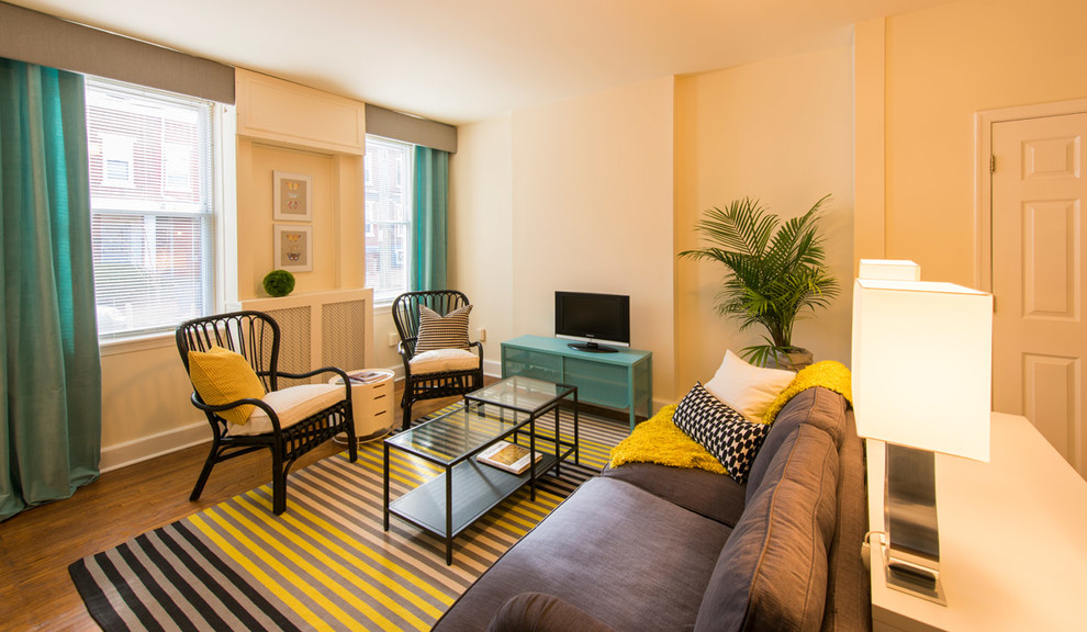 Immagine di un soggiorno contemporaneo aperto con pareti beige, pavimento in legno massello medio, nessun camino e TV autoportante