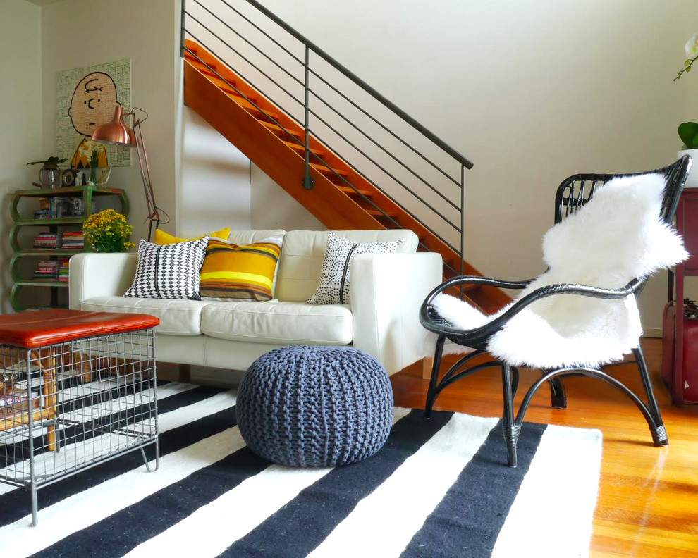 Living room - eclectic medium tone wood floor and orange floor living room idea in Melbourne with white walls