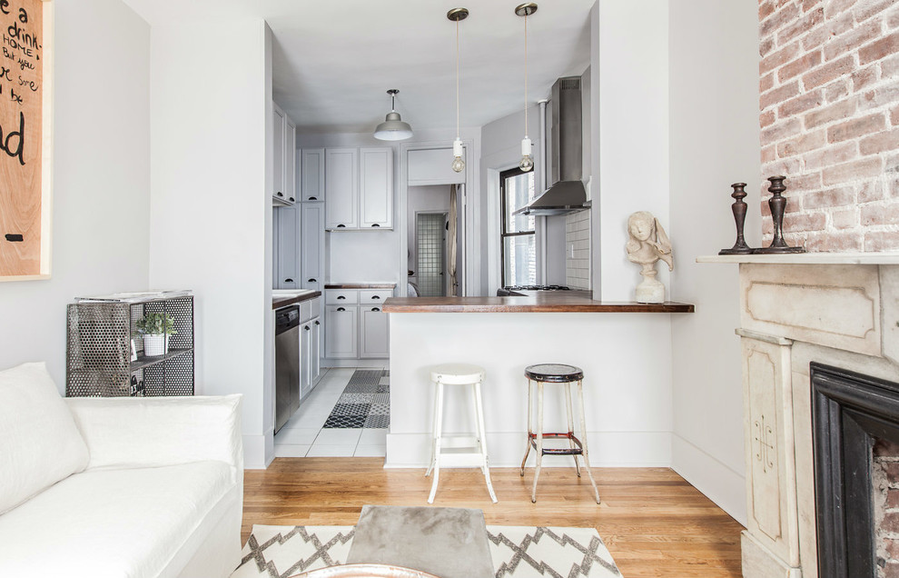 Small eclectic enclosed medium tone wood floor living room photo in New York with gray walls, a standard fireplace and no tv