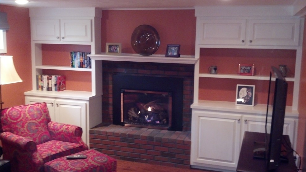 Cette image montre un salon traditionnel de taille moyenne et fermé avec une salle de réception, un mur orange, parquet foncé, une cheminée standard, un manteau de cheminée en brique, aucun téléviseur et un sol marron.