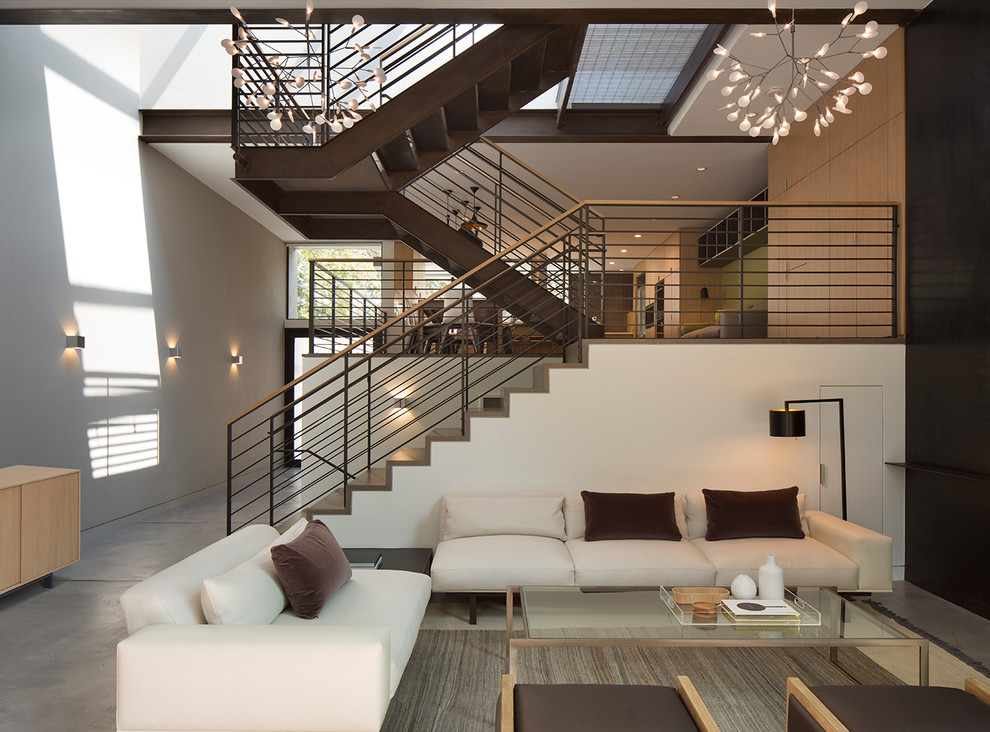 Immagine di un piccolo soggiorno minimalista stile loft con angolo bar, pareti bianche, pavimento in cemento, camino classico, cornice del camino in metallo e TV a parete