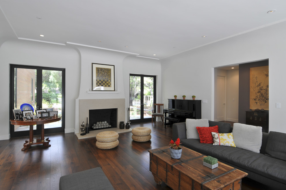 Cette photo montre un salon tendance avec un mur blanc, une cheminée standard, une bibliothèque ou un coin lecture et un sol en bois brun.