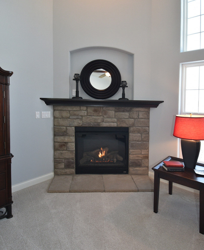 ミルウォーキーにあるお手頃価格の広いトラディショナルスタイルのおしゃれなLDK (グレーの壁、カーペット敷き、コーナー設置型暖炉、石材の暖炉まわり) の写真