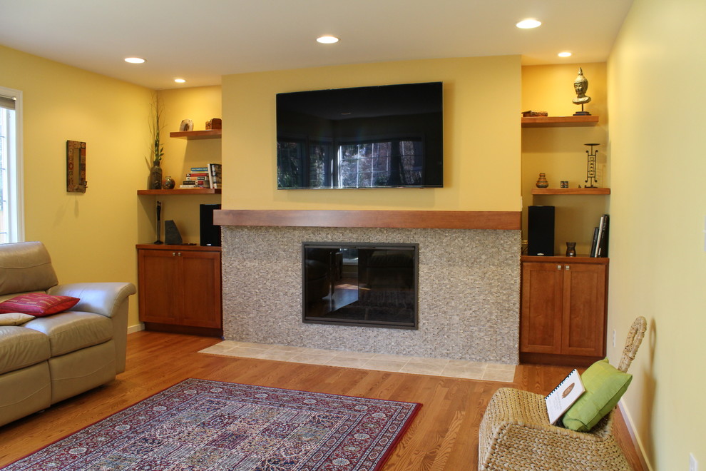 Mittelgroßes, Repräsentatives, Abgetrenntes Modernes Wohnzimmer mit gelber Wandfarbe, braunem Holzboden, Kamin, gefliester Kaminumrandung und TV-Wand in Seattle
