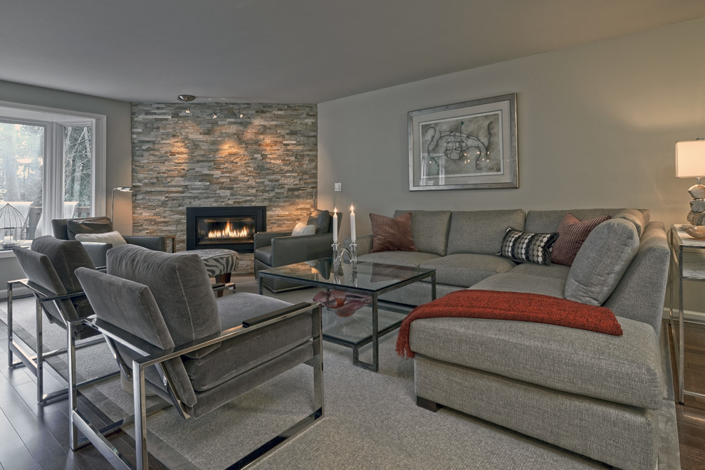 Пример оригинального дизайна: открытая гостиная комната в современном стиле с серыми стенами, паркетным полом среднего тона, стандартным камином и фасадом камина из камня