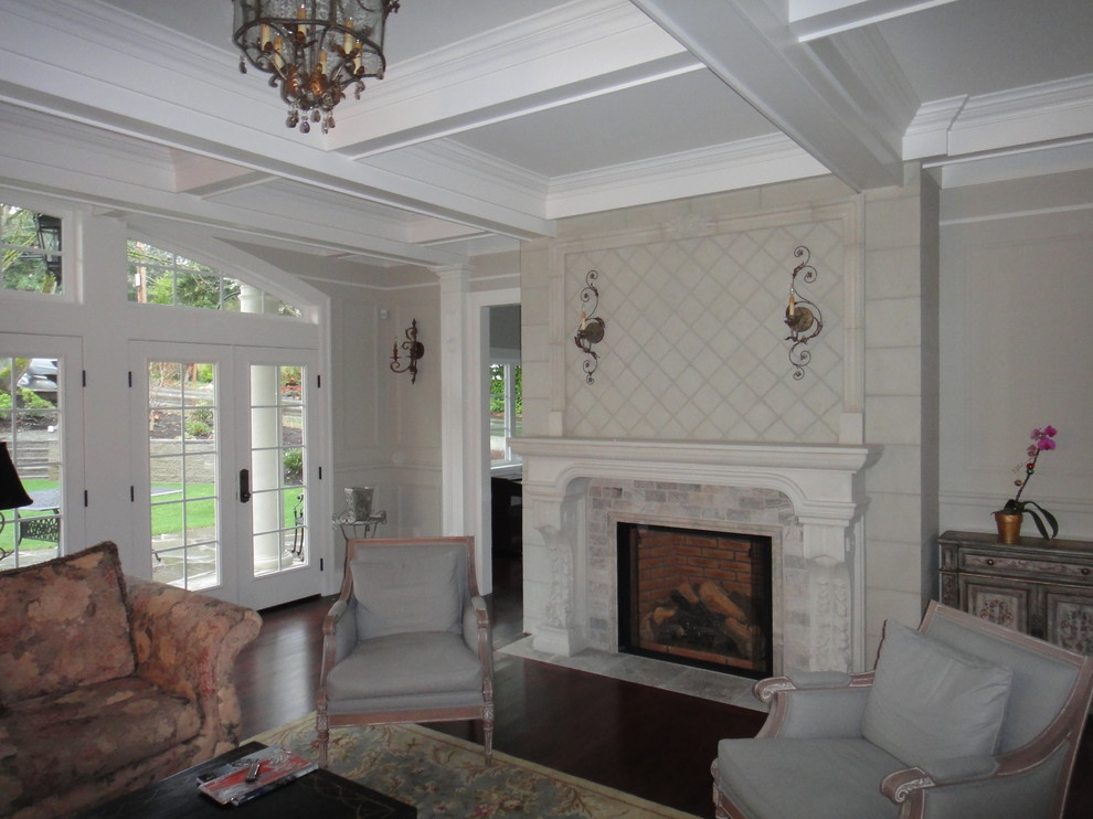 Inspiration pour un grand salon traditionnel ouvert avec un mur gris, parquet foncé, une cheminée standard, un manteau de cheminée en pierre et un sol marron.