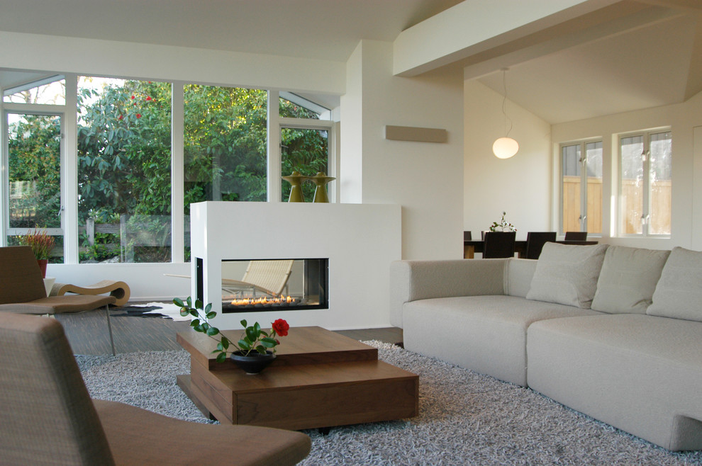 Imagen de salón abierto minimalista con paredes blancas, suelo de madera oscura y chimenea de doble cara