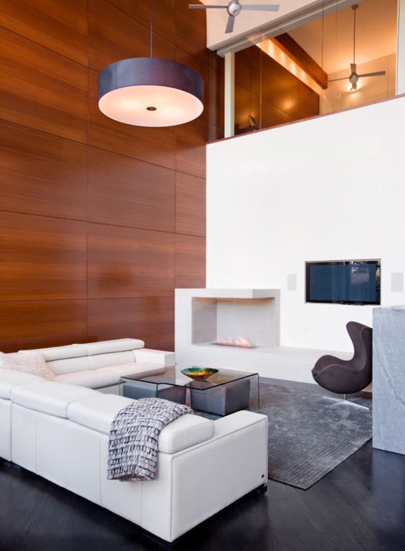 На фото: большая открытая гостиная комната в современном стиле с белыми стенами, темным паркетным полом, двусторонним камином, фасадом камина из плитки и телевизором на стене с