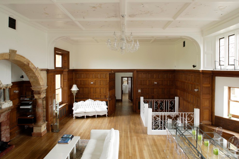 Идея дизайна: огромная гостиная комната в стиле фьюжн с белыми стенами, светлым паркетным полом, стандартным камином и фасадом камина из камня