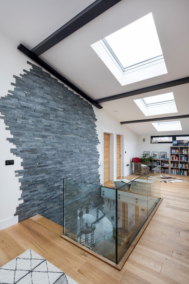 Repräsentatives, Offenes Modernes Wohnzimmer mit grauer Wandfarbe, hellem Holzboden, Eckkamin, verputzter Kaminumrandung, TV-Wand und braunem Boden in Essex