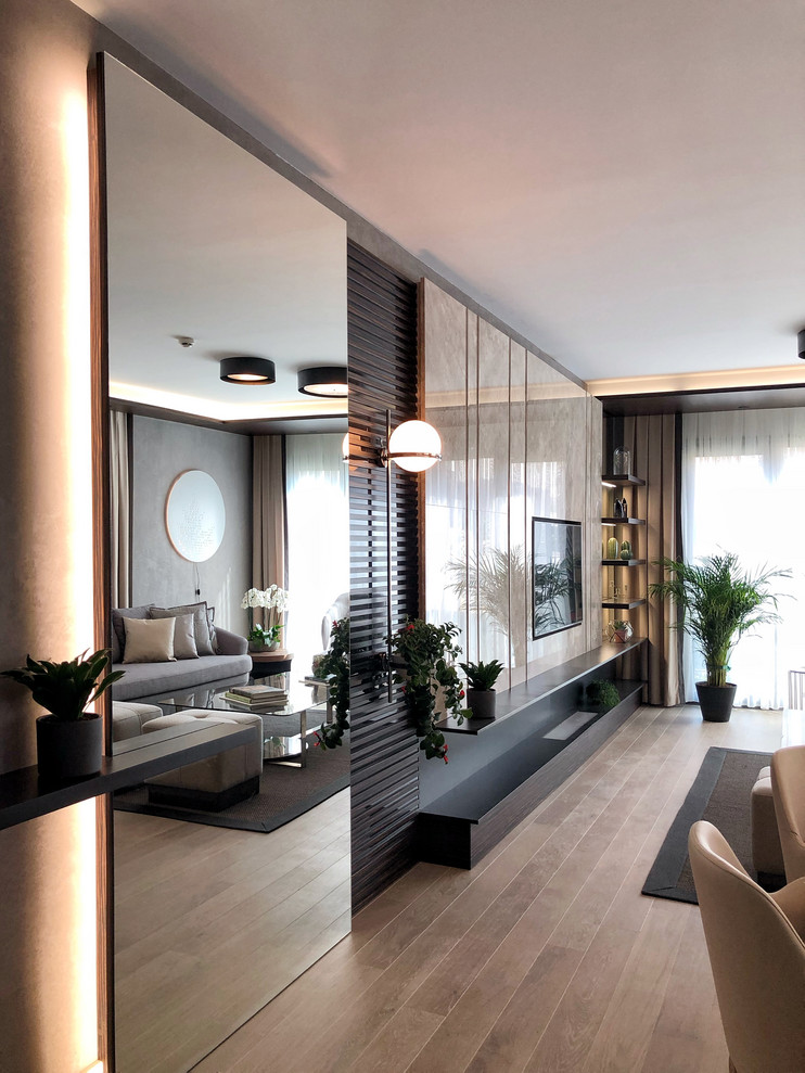Inspiration pour un grand salon minimaliste avec un mur beige, sol en stratifié, aucune cheminée, un téléviseur encastré et du lambris.