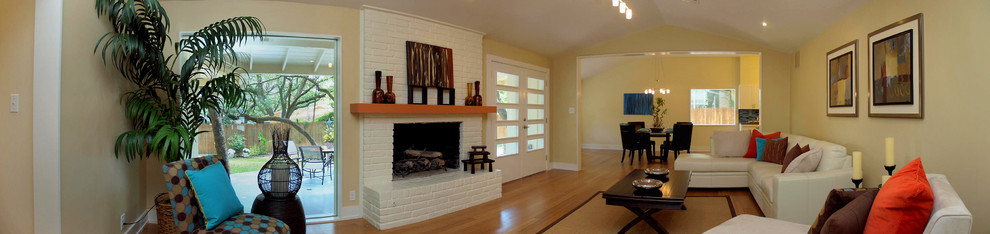 Стильный дизайн: открытая гостиная комната среднего размера в стиле фьюжн с стандартным камином и фасадом камина из кирпича - последний тренд