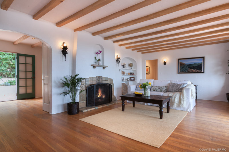 Aménagement d'un grand salon méditerranéen ouvert avec un mur blanc, un sol en bois brun, une cheminée standard et un manteau de cheminée en carrelage.