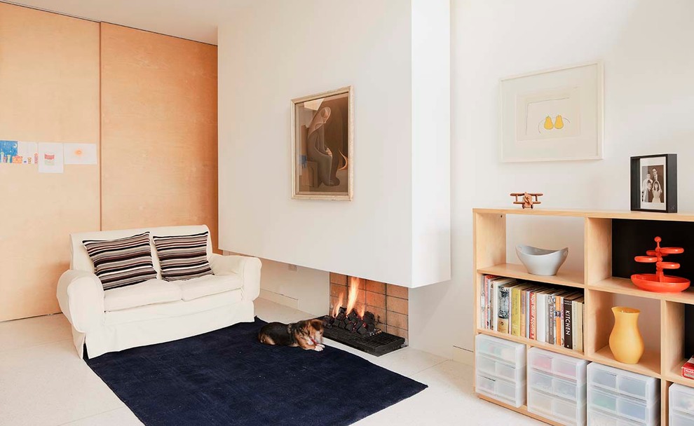 Medium sized scandi open plan living room in Dublin with a reading nook, white walls, no tv, concrete flooring, a hanging fireplace, a brick fireplace surround and white floors.