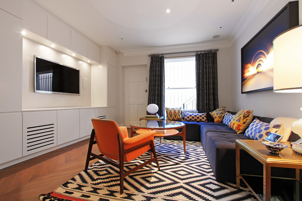 Foto de salón cerrado tradicional renovado de tamaño medio con paredes grises, suelo de madera en tonos medios y televisor colgado en la pared