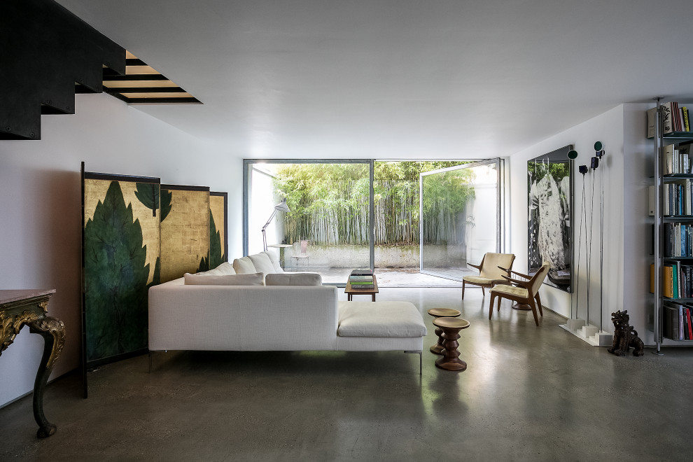 Foto di un grande soggiorno moderno aperto con pareti bianche, pavimento in cemento, nessun camino, nessuna TV e pavimento grigio