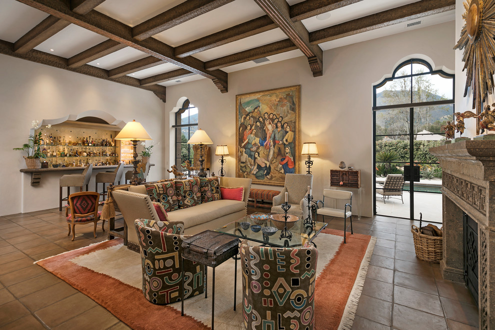 This is an example of a large mediterranean open plan living room in Santa Barbara with a home bar, beige walls, terracotta flooring, a standard fireplace, a stone fireplace surround and no tv.