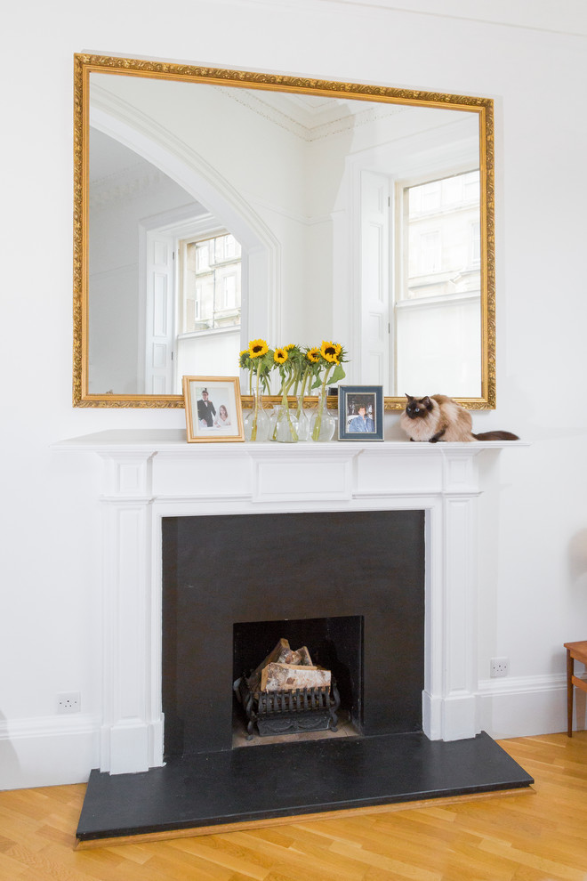 This is an example of a small contemporary formal open plan living room in Edinburgh with white walls, medium hardwood flooring, a standard fireplace, a stone fireplace surround and no tv.