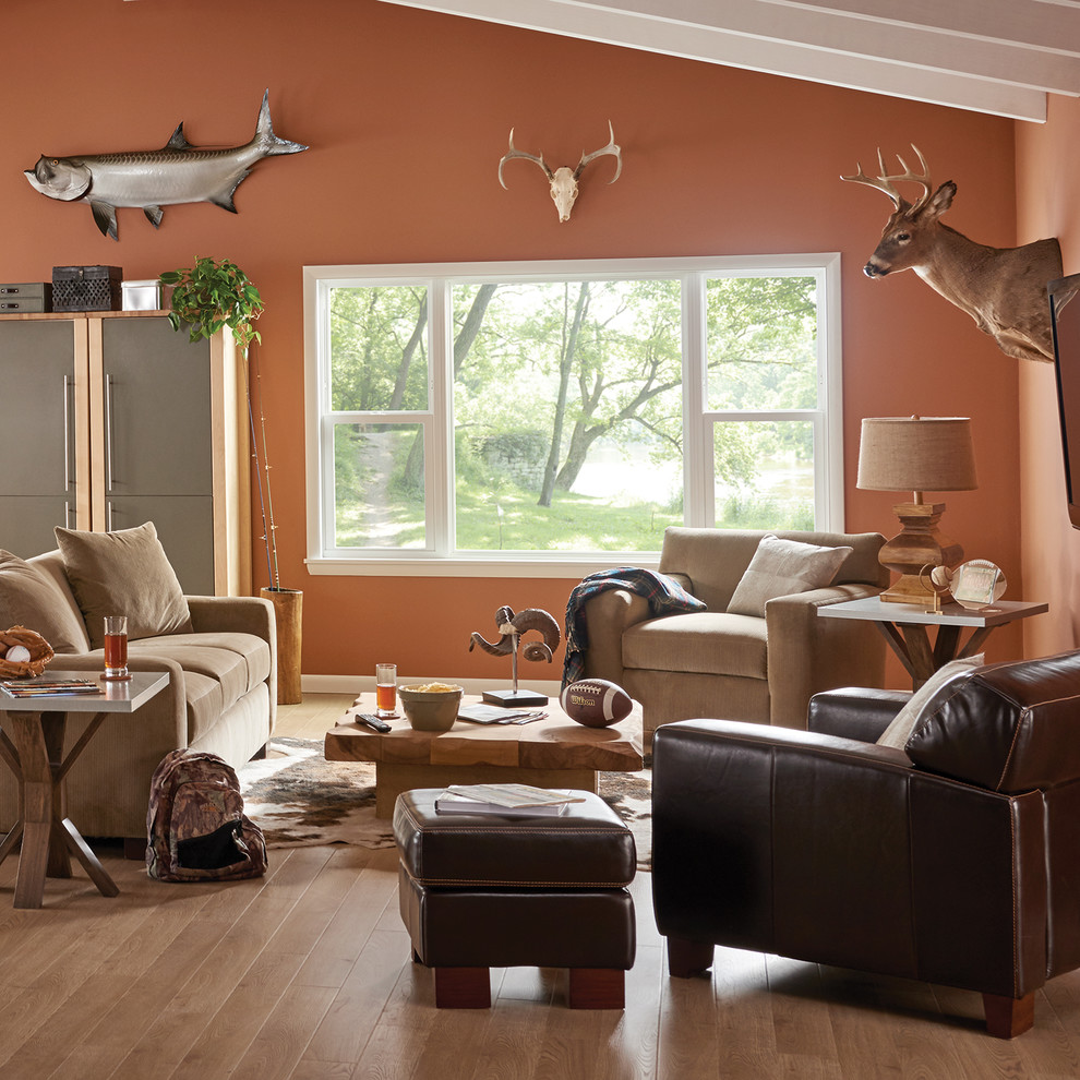 Diseño de salón abierto de estilo americano pequeño sin chimenea con parades naranjas, suelo de madera en tonos medios, televisor colgado en la pared y suelo marrón