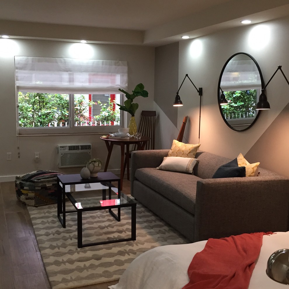 Modelo de salón abierto minimalista de tamaño medio sin chimenea con paredes beige, suelo de madera clara y televisor colgado en la pared