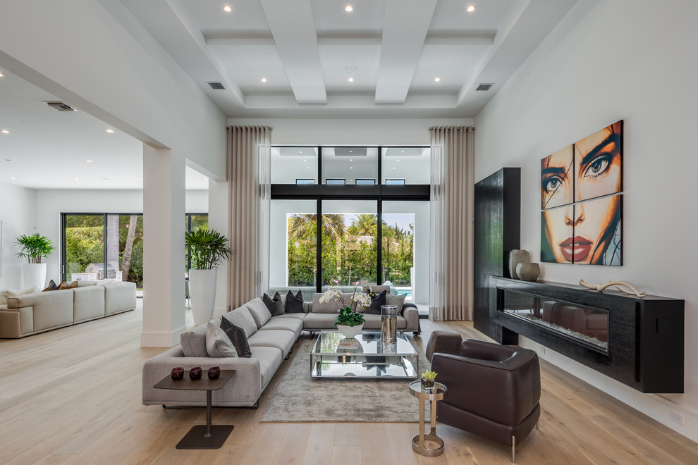Geräumiges, Offenes Modernes Wohnzimmer mit weißer Wandfarbe, braunem Holzboden, Gaskamin und braunem Boden in Miami