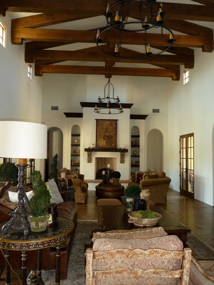 Großes, Repräsentatives, Abgetrenntes Mediterranes Wohnzimmer mit weißer Wandfarbe, braunem Holzboden, Kamin, Kaminumrandung aus Beton und braunem Boden in Phoenix
